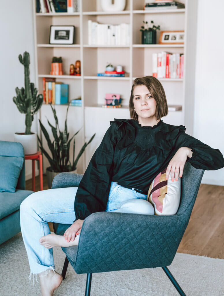 Frau sitzt auf einem Stuhl und schaut in die Kamera